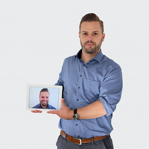 H. Spies lächelt mit eine Bild von sich in der Hand.